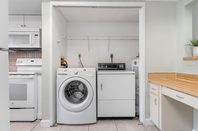 clothes washing area featuring washer and clothes dryer and light tile patterned floors