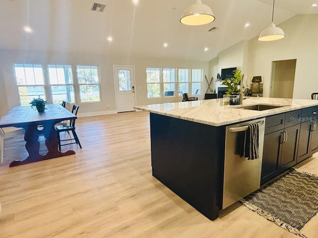 kitchen featuring sink, hanging light fixtures, stainless steel dishwasher, an island with sink, and light wood-type flooring