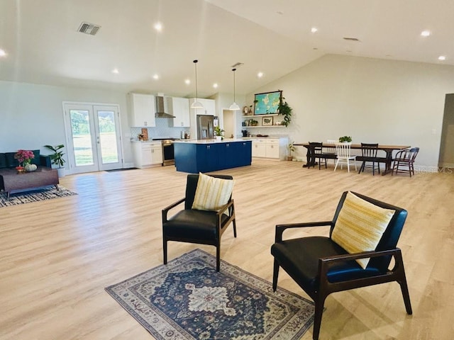 living room featuring french doors, light hardwood / wood-style floors, and lofted ceiling