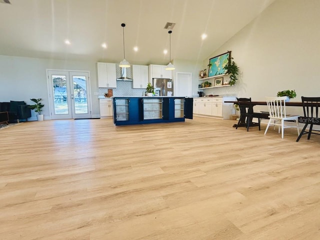 kitchen featuring stainless steel refrigerator, wall chimney exhaust hood, light hardwood / wood-style floors, decorative light fixtures, and white cabinets