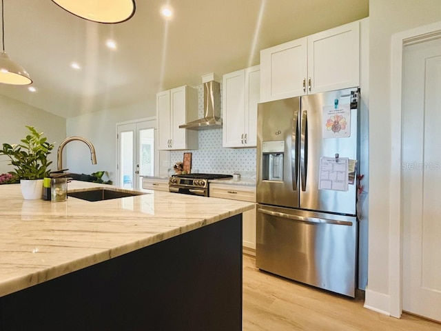 kitchen with appliances with stainless steel finishes, white cabinetry, and wall chimney range hood