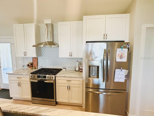 kitchen with white cabinetry, wall chimney exhaust hood, light stone counters, and appliances with stainless steel finishes