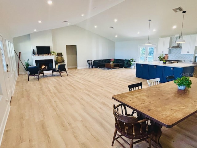 dining area with french doors, light hardwood / wood-style flooring, and lofted ceiling