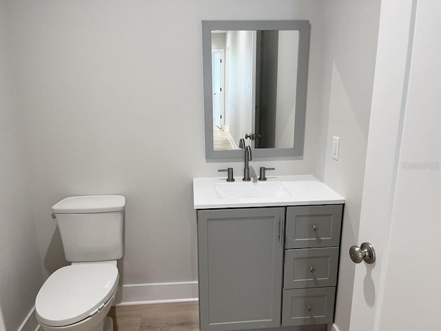 bathroom with hardwood / wood-style floors, vanity, and toilet