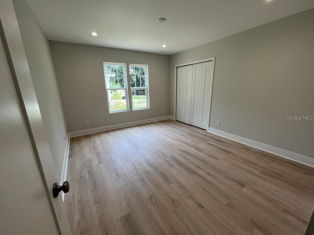 unfurnished bedroom featuring light hardwood / wood-style flooring and a closet