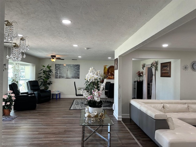 living room with a textured ceiling, ceiling fan, and dark wood-type flooring