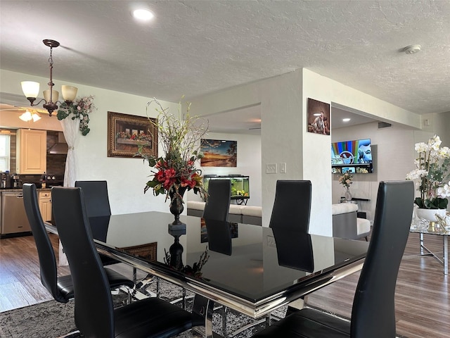 dining space featuring a textured ceiling, ceiling fan with notable chandelier, and wood-type flooring