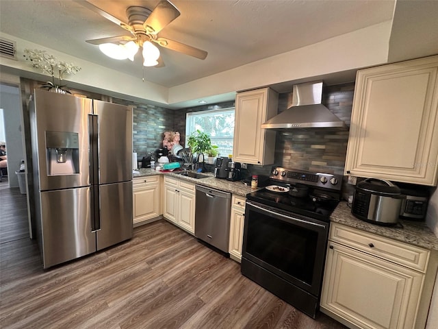 kitchen with backsplash, dark hardwood / wood-style flooring, ceiling fan, stainless steel appliances, and wall chimney range hood