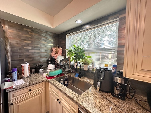 kitchen with sink, light stone counters, and cream cabinetry