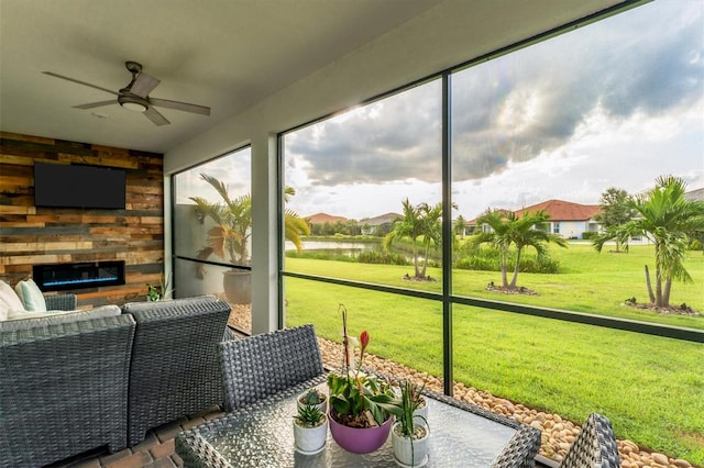 sunroom / solarium featuring ceiling fan and an outdoor stone fireplace