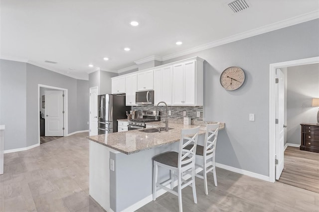 kitchen with stainless steel appliances, decorative backsplash, light stone counters, light wood-type flooring, and white cabinets