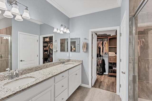 bathroom featuring an enclosed shower, crown molding, and dual bowl vanity