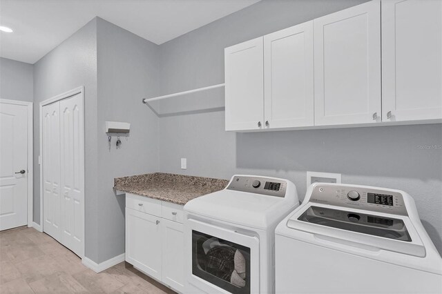 laundry room with light hardwood / wood-style flooring, washing machine and dryer, and cabinets