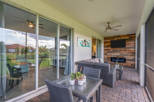 sunroom / solarium with ceiling fan and a fireplace