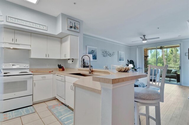 kitchen featuring kitchen peninsula, a breakfast bar, white appliances, ceiling fan, and sink