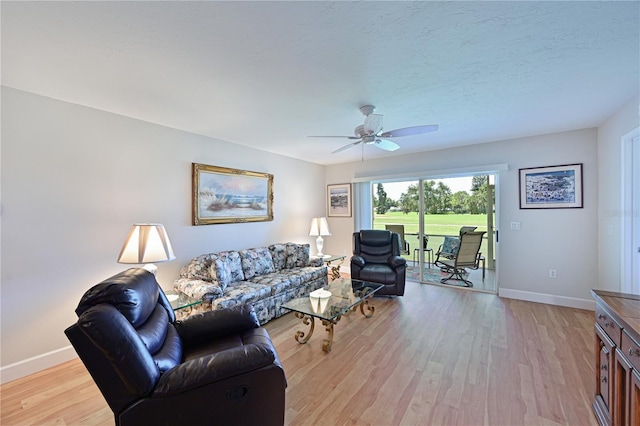 living room with ceiling fan, a textured ceiling, and light wood-type flooring