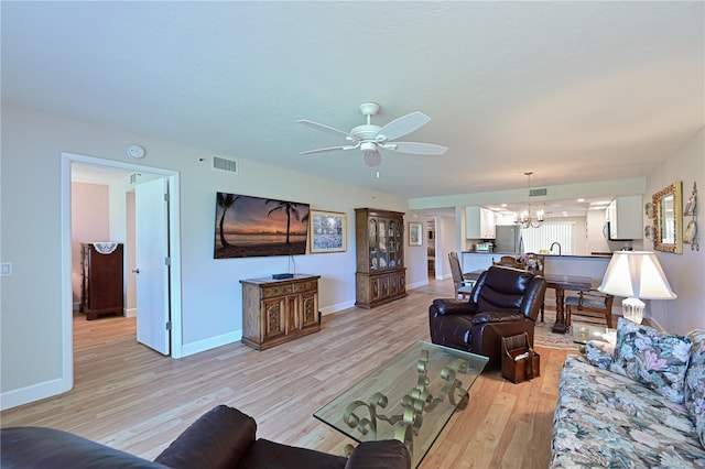 living room featuring ceiling fan with notable chandelier and light hardwood / wood-style floors