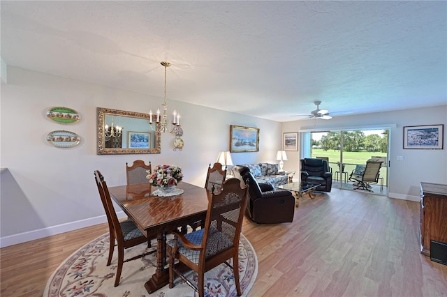 dining area featuring ceiling fan with notable chandelier, a textured ceiling, and light hardwood / wood-style floors