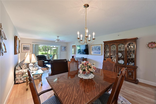 dining area with ceiling fan with notable chandelier and light hardwood / wood-style floors