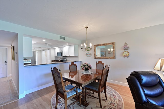 dining room featuring ceiling fan with notable chandelier and light hardwood / wood-style floors