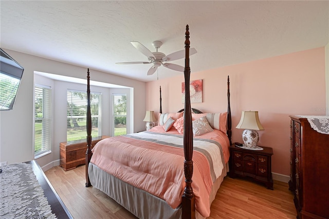 bedroom with ceiling fan, a textured ceiling, and light hardwood / wood-style flooring