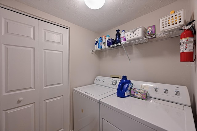 clothes washing area featuring washing machine and clothes dryer and a textured ceiling