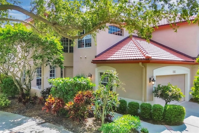 view of front of home with a garage, a tiled roof, and stucco siding