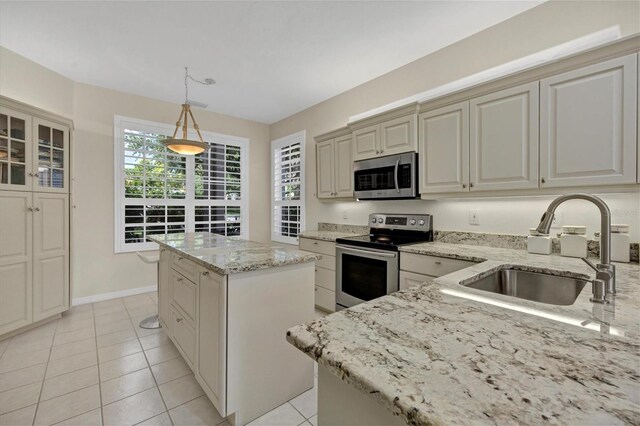 kitchen with light tile patterned flooring, sink, a kitchen island, stainless steel appliances, and pendant lighting