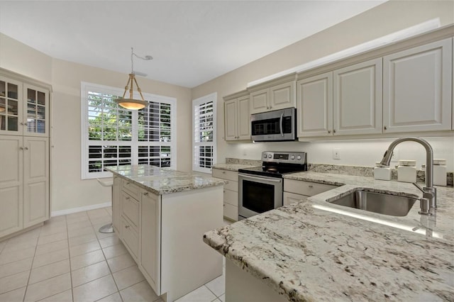 kitchen featuring a center island, stainless steel appliances, hanging light fixtures, glass insert cabinets, and a sink