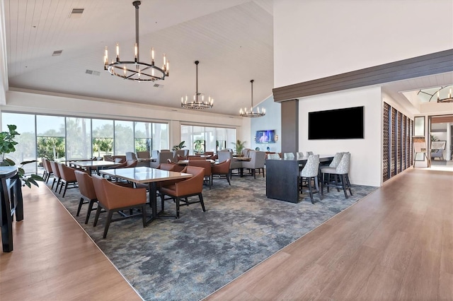 dining area featuring high vaulted ceiling, wood-type flooring, and a chandelier