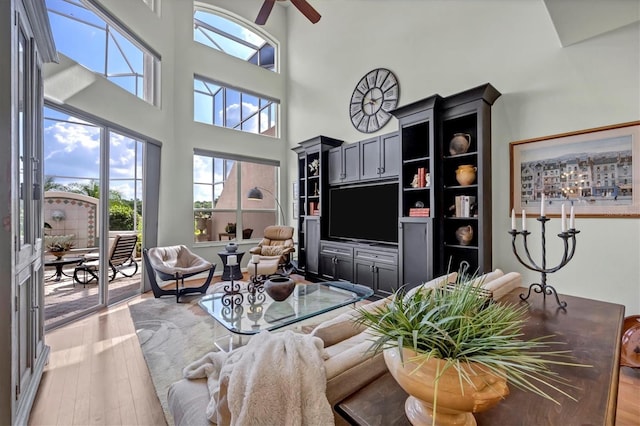 living room with ceiling fan, light hardwood / wood-style floors, and a high ceiling