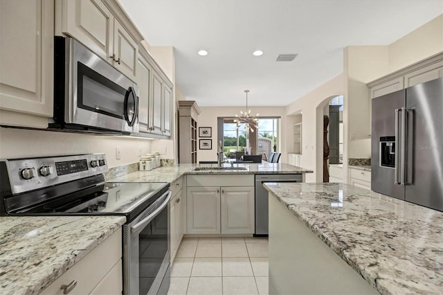 kitchen featuring pendant lighting, appliances with stainless steel finishes, light tile patterned floors, sink, and an inviting chandelier