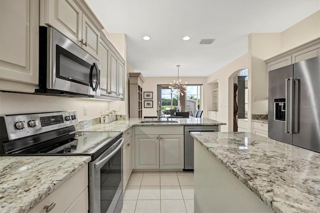 kitchen featuring light tile patterned floors, a sink, visible vents, appliances with stainless steel finishes, and decorative light fixtures