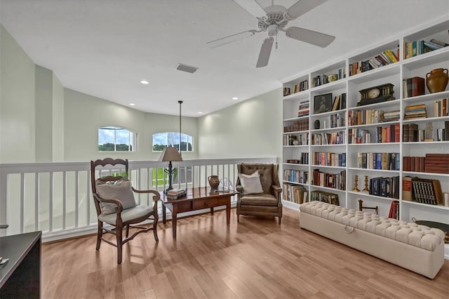 living area with ceiling fan, light wood-type flooring, and built in features