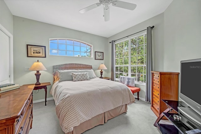 bedroom with a ceiling fan, light colored carpet, and baseboards