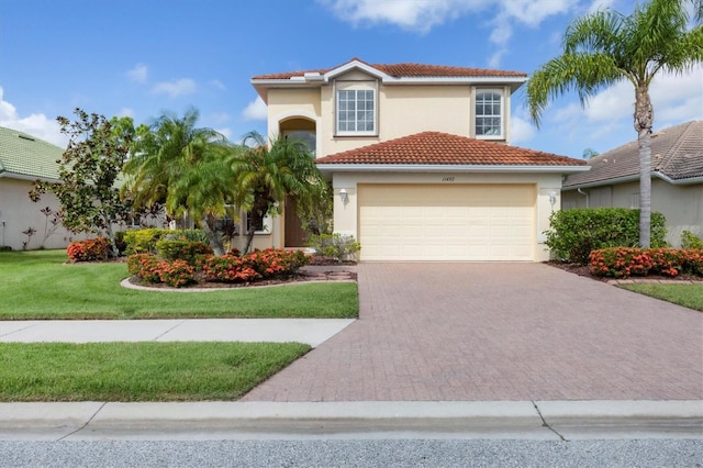 mediterranean / spanish-style home with a front yard, decorative driveway, a tiled roof, and stucco siding