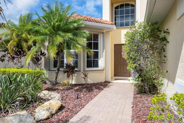 property entrance with a tile roof and stucco siding