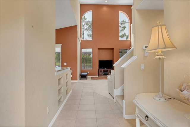 interior space featuring stairs, light tile patterned flooring, a towering ceiling, and plenty of natural light