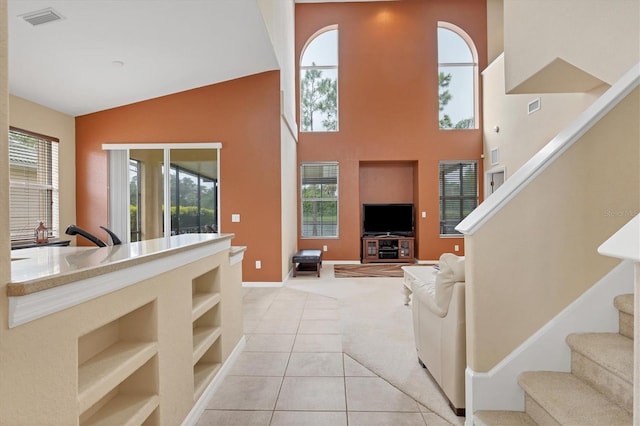 living room featuring light tile patterned floors, stairs, visible vents, and light colored carpet