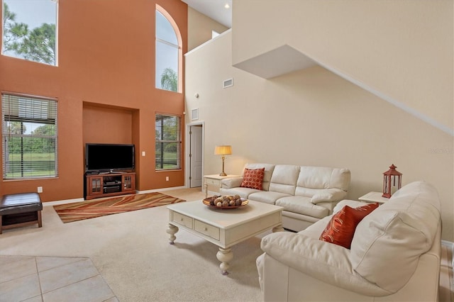 carpeted living room with a wealth of natural light, visible vents, and tile patterned floors