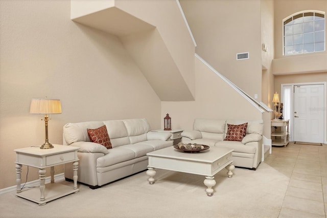 living room featuring light tile patterned floors, a high ceiling, and visible vents