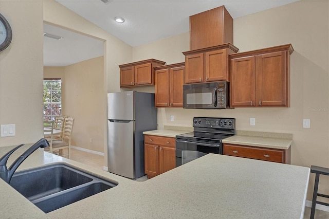 kitchen with a sink, baseboards, light countertops, brown cabinets, and black appliances