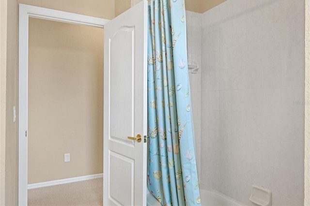 bathroom featuring shower / tub combo and baseboards