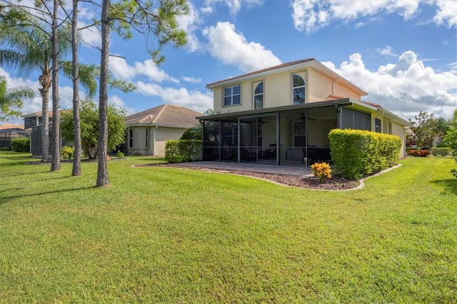 back of house featuring a sunroom, ceiling fan, stucco siding, and a yard