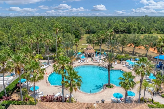 community pool featuring a gazebo, a forest view, and a patio