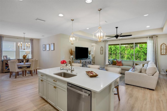 kitchen with decorative light fixtures, dishwasher, sink, white cabinets, and a kitchen island with sink