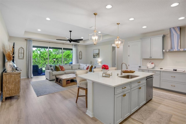 kitchen featuring a raised ceiling, light hardwood / wood-style flooring, wall chimney exhaust hood, and sink