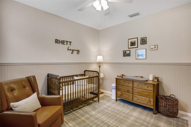 bedroom with carpet, a crib, and ceiling fan