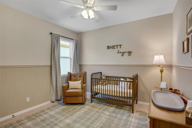 bedroom with carpet floors, a nursery area, and ceiling fan