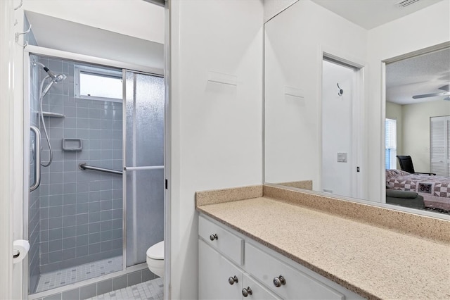 bathroom with toilet, tile patterned flooring, vanity, a tile shower, and ceiling fan